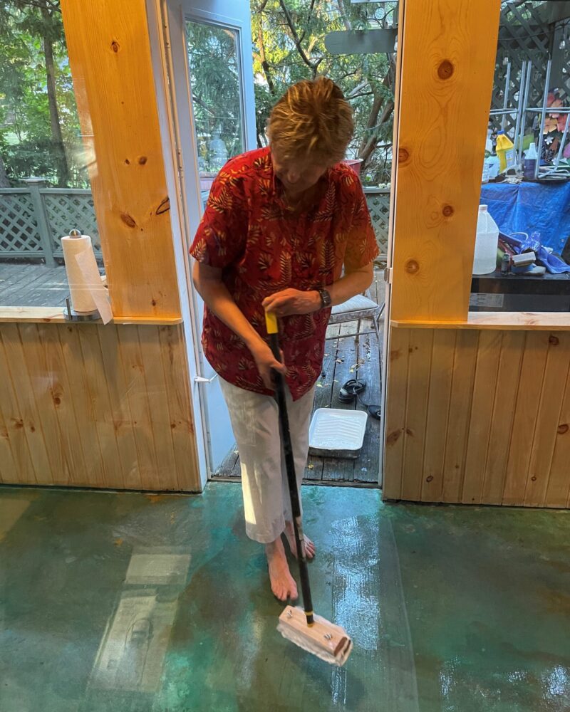 A woman applying ProWax Polish floor wax on the stained porch floor using a mop