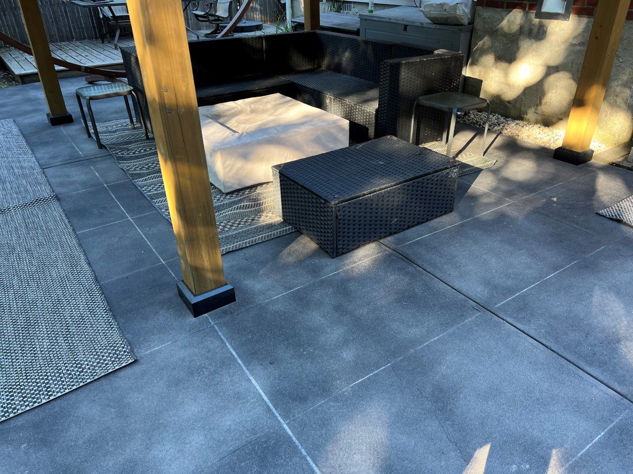 Black Antiquing stained concrete patio surface with tape creating a large tile design pattern.
