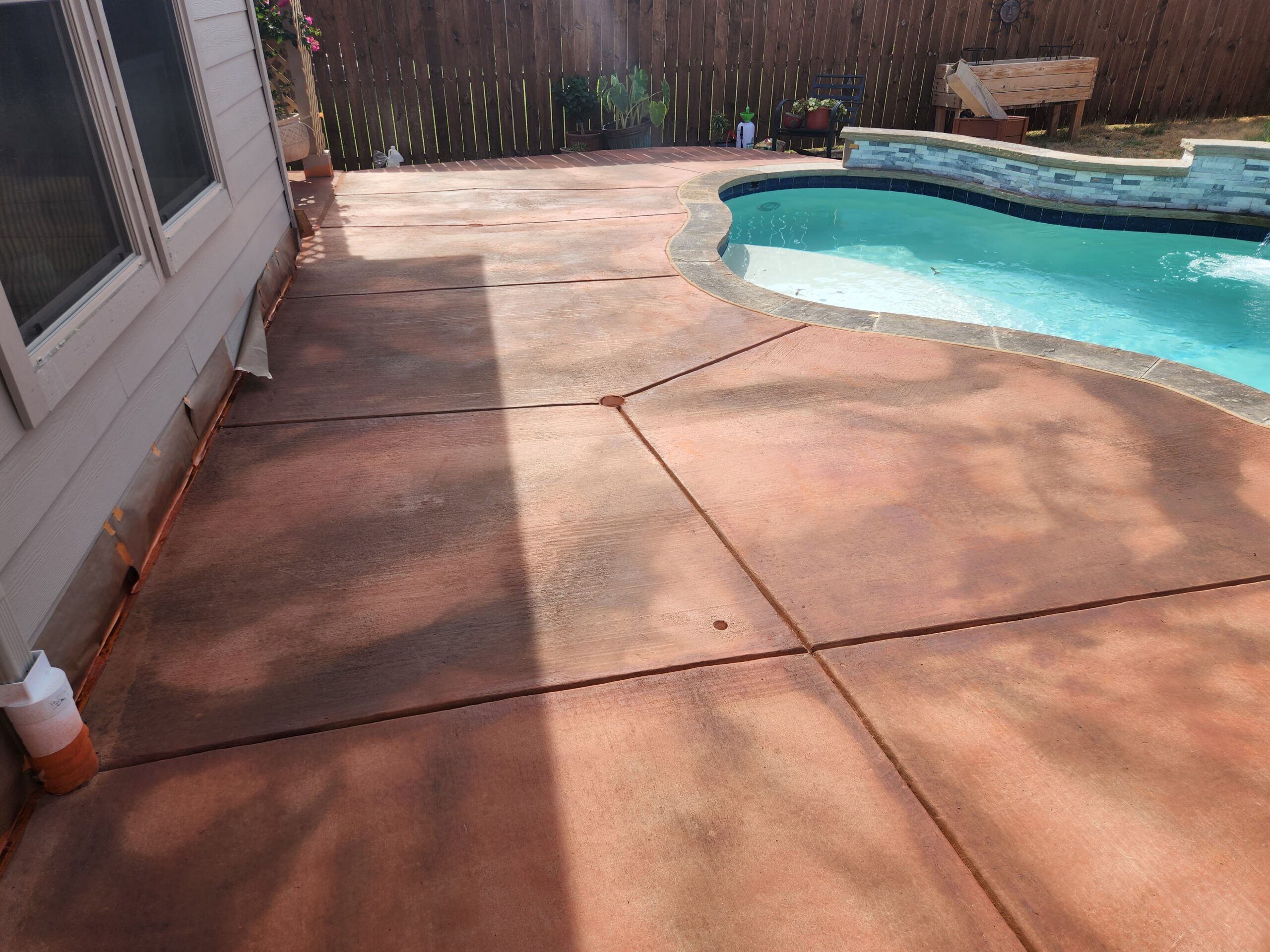 Stained concrete pool deck featuring a warm Terracotta base color and highlighted with driftwood hues