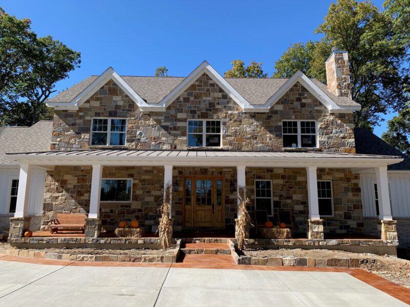 Cola EverStain acid stain accentuates the charming character of the home's stonework and autumnal decor, unifying the entryway and driveway in a cohesive and inviting manner.