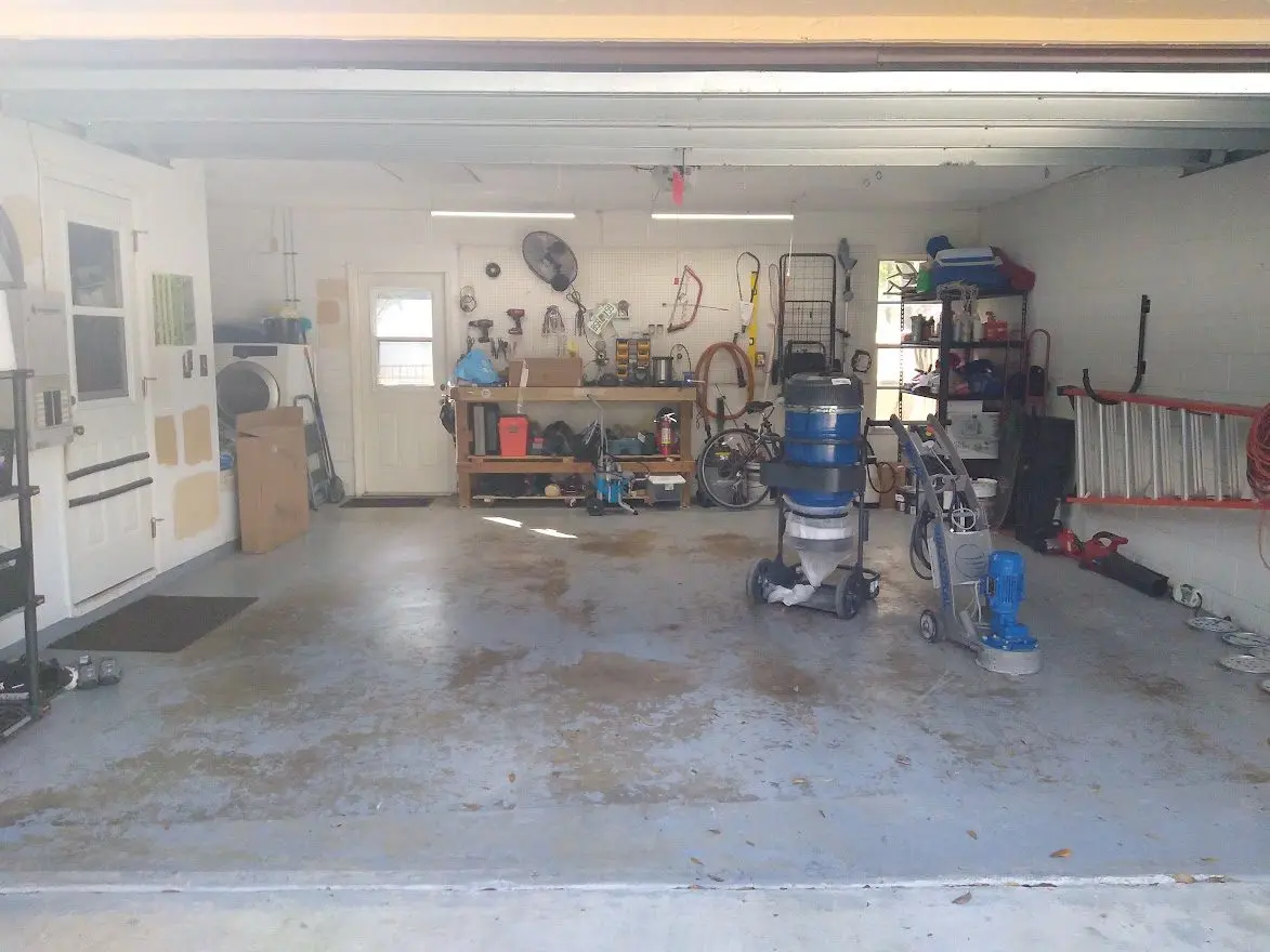 Unappealing garage with peeling coating and sealant on the floor, left behind by the previous owner