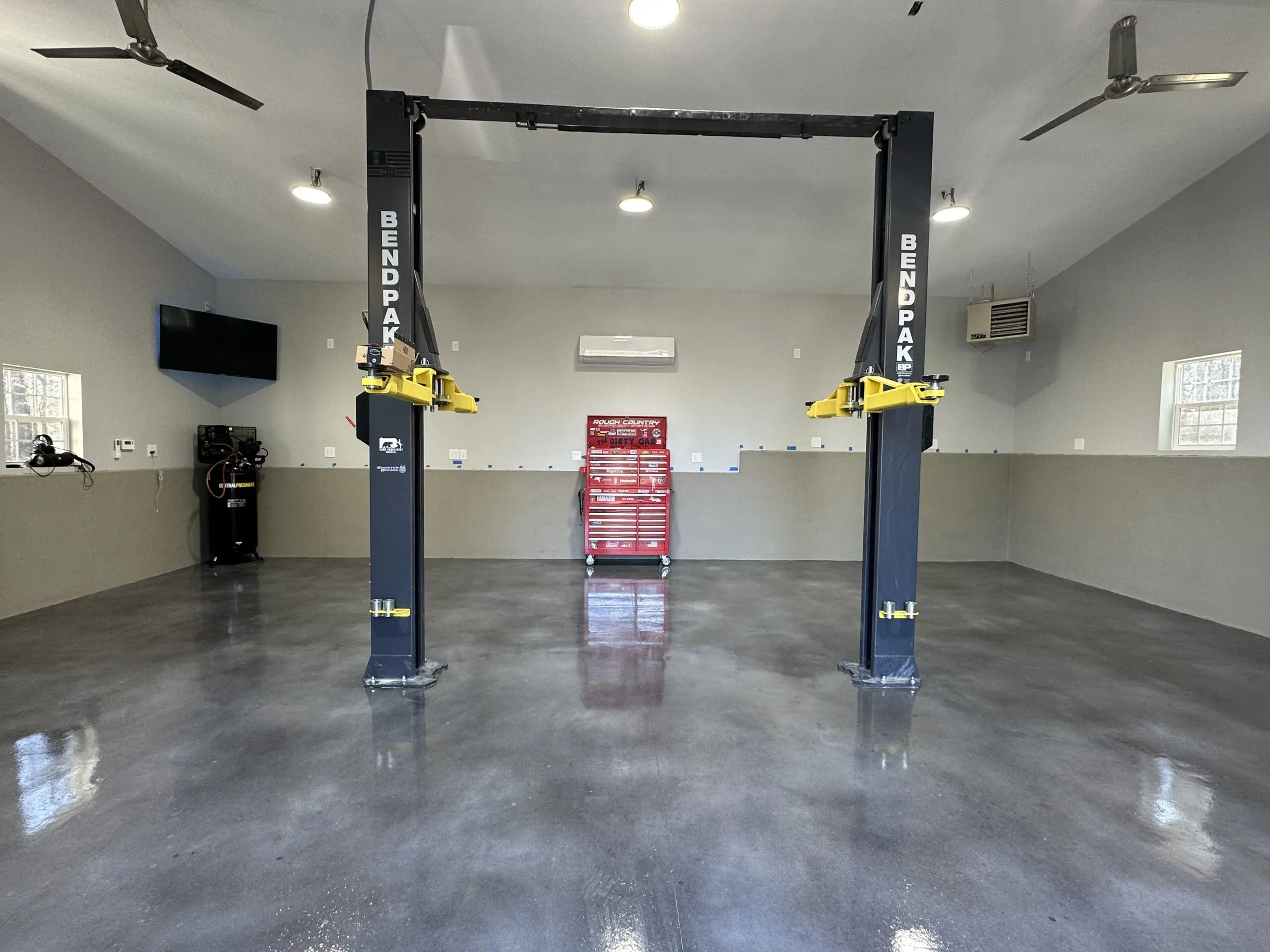 A striking transformation of a plain concrete garage floor into a unique, eye-catching surface using Vibrance concrete dye in charcoal, stormy gray, and white shades
