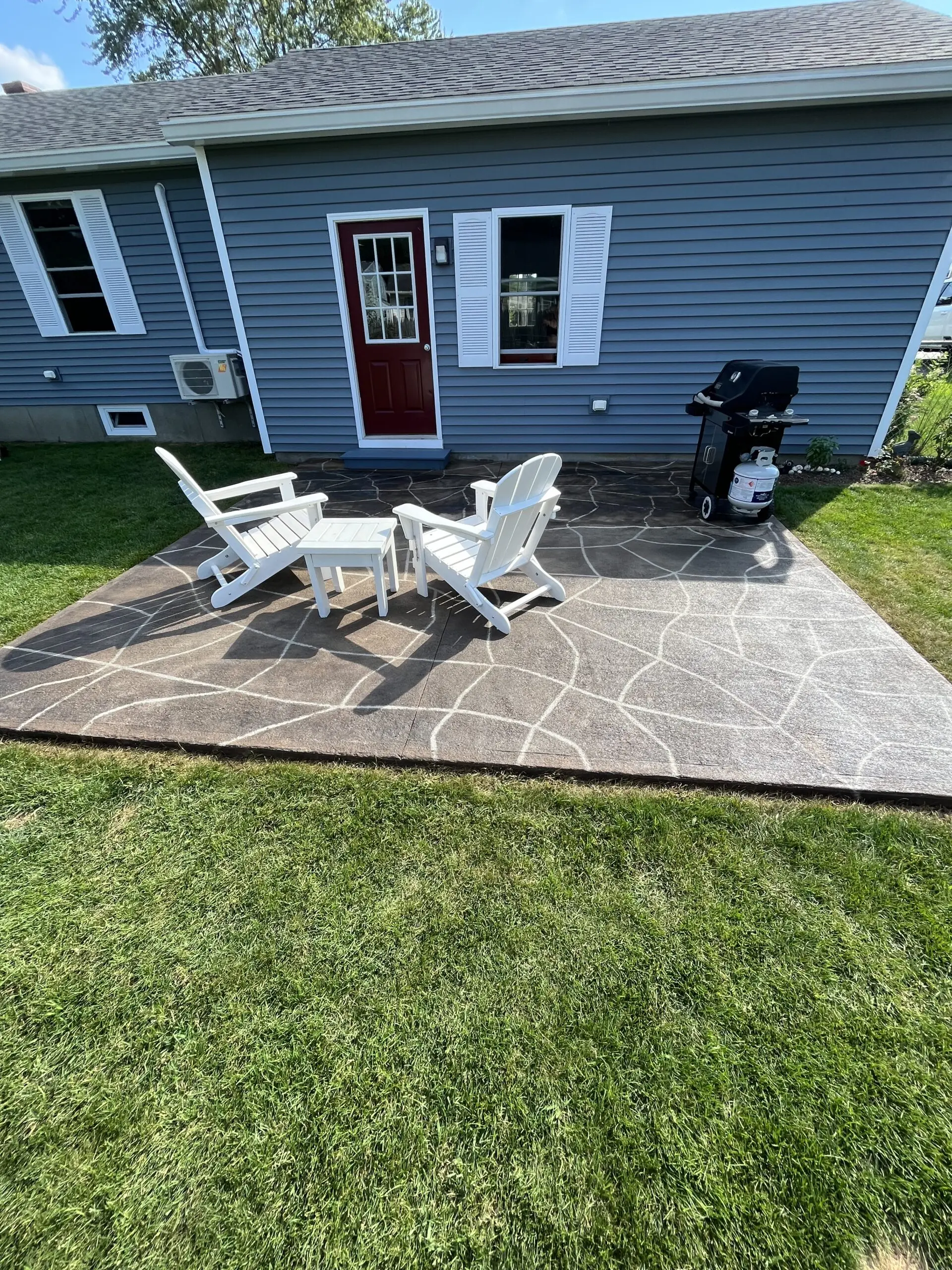 The transformed patio featuring the faux flagstone design, furnished with outdoor chairs and tables