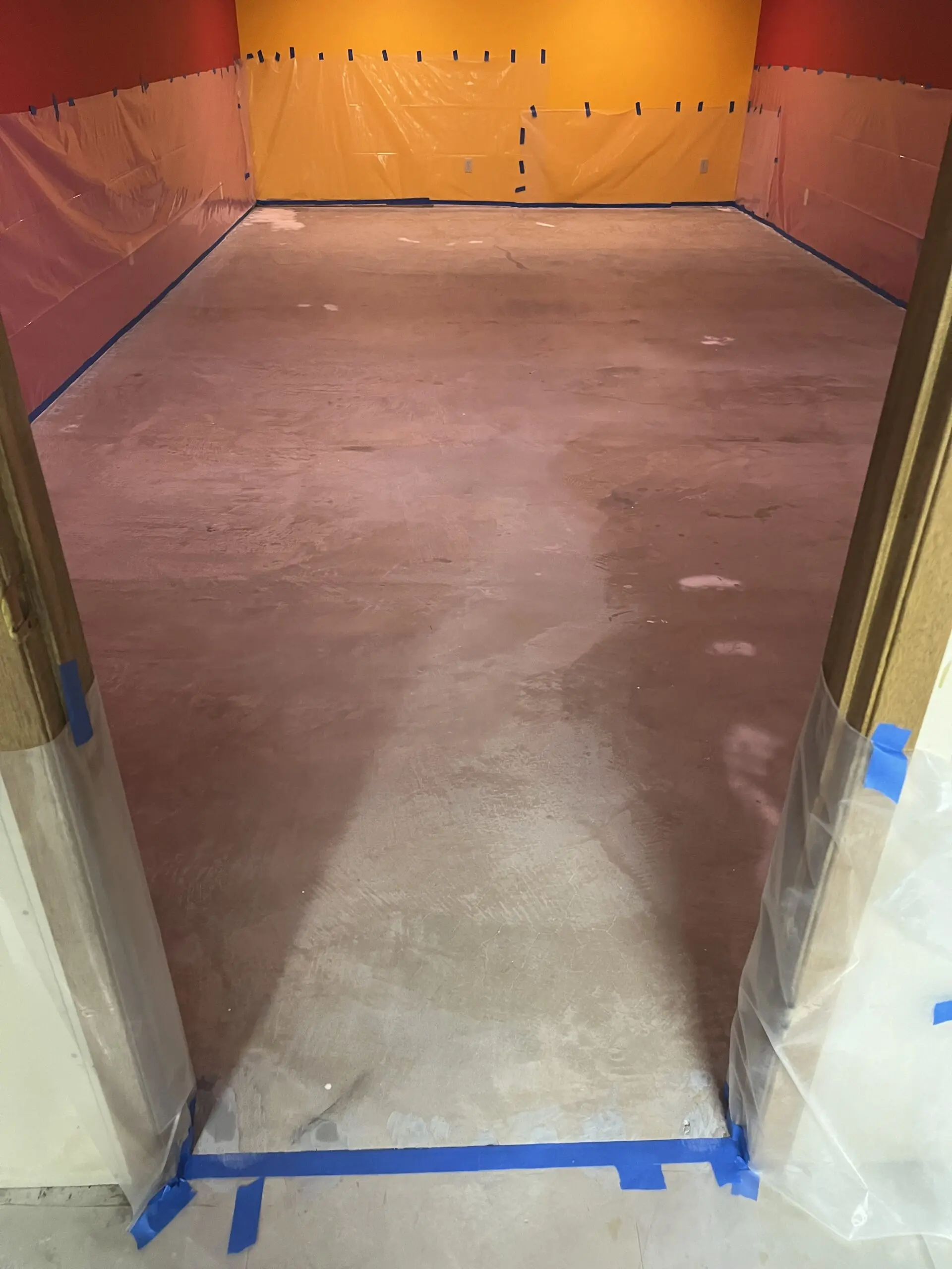 Unfinished floor with visible imperfections and paint spots prior to staining