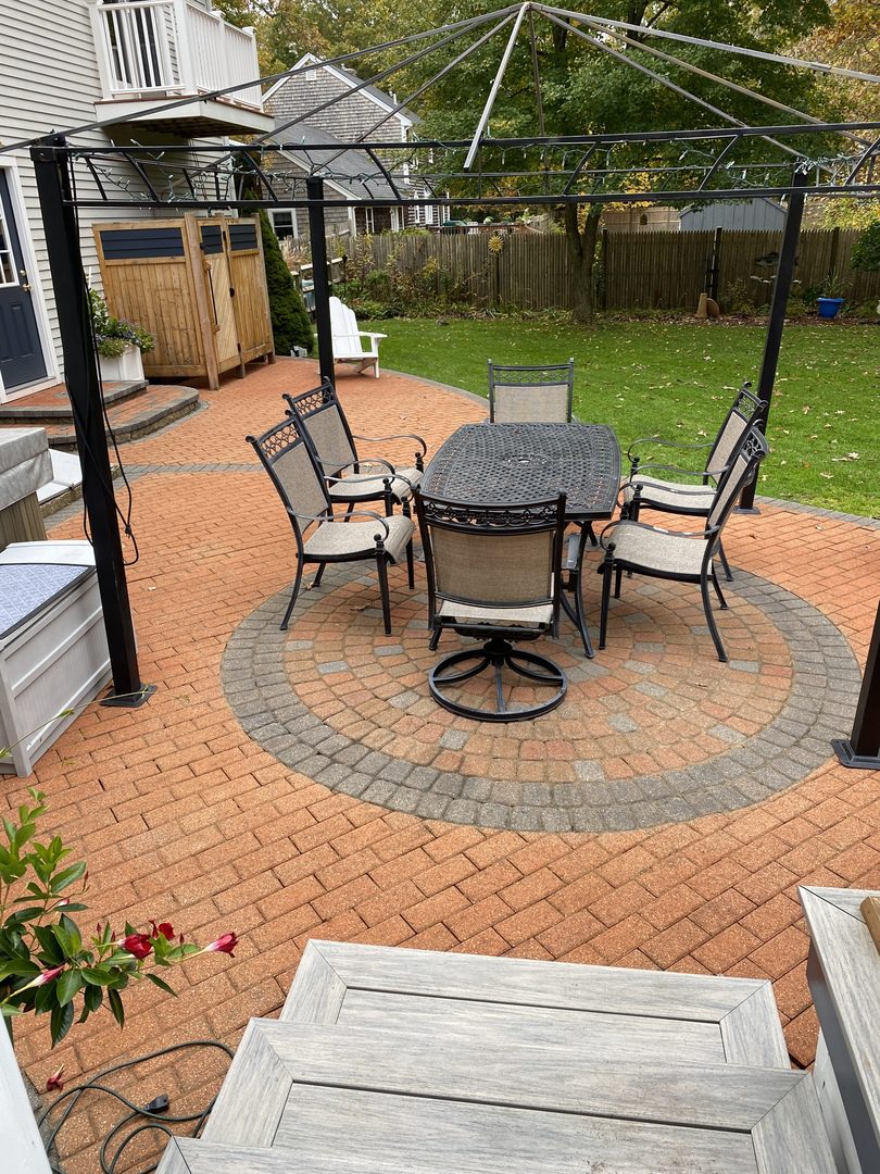 Terracotta stained patio with circular paver design in warm earthy tones & charcoal border.