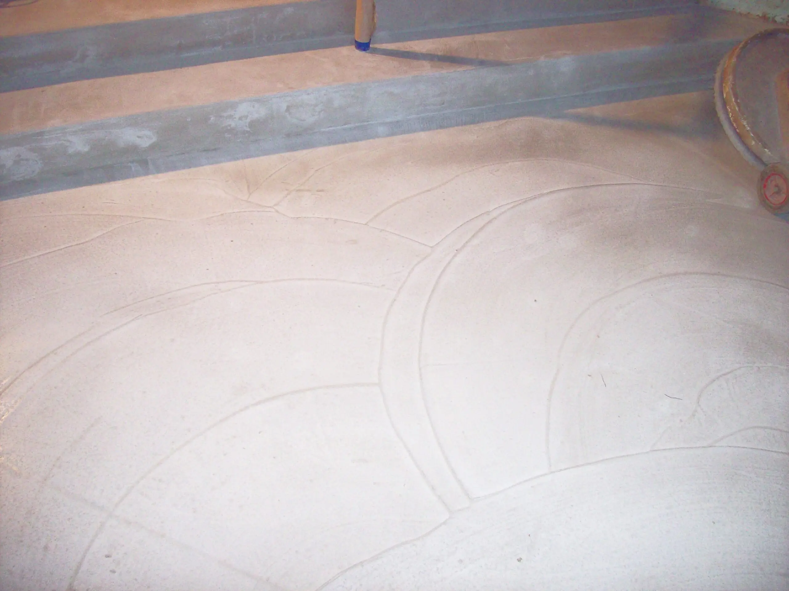Using a trowel to create a swirling pattern on the surface of the wet concrete overlay