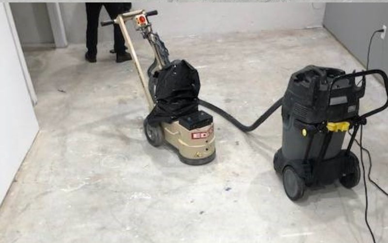 Rented concrete grinder being used to remove old stains and paint from concrete surface