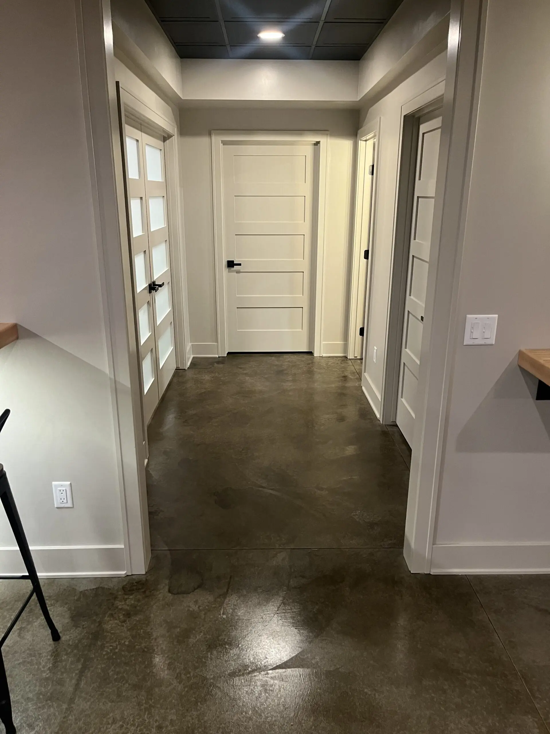 A modern entryway featuring a dark brown concrete floor stained with ColorWave Molasses, complementing contemporary decor.