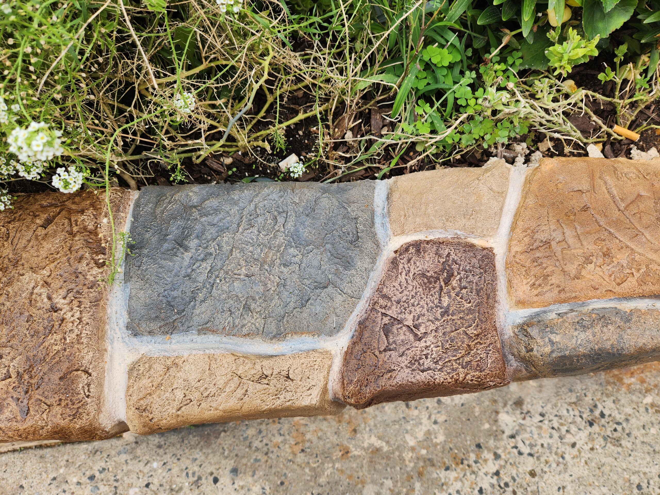 Detailed view of a faux stone concrete retaining wall with mixed stains