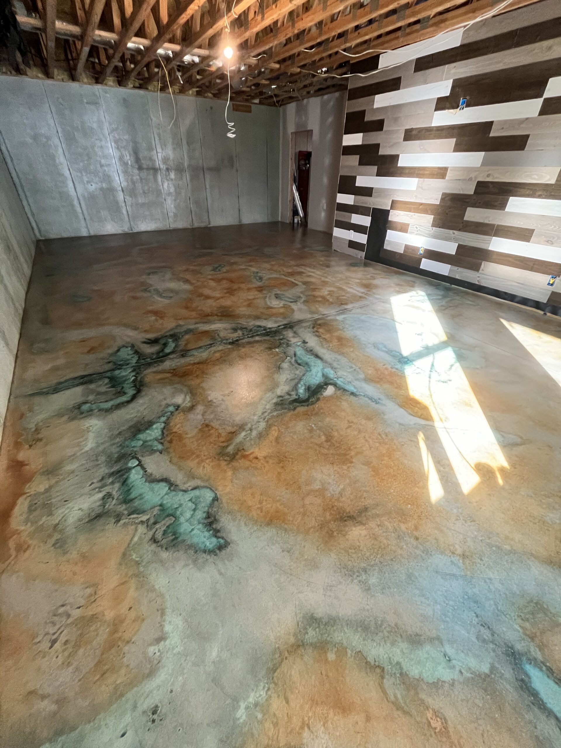 Finished man cave with a concrete floor stained using Seagrass and Malayan Buff, featuring bold blue veining patterns.