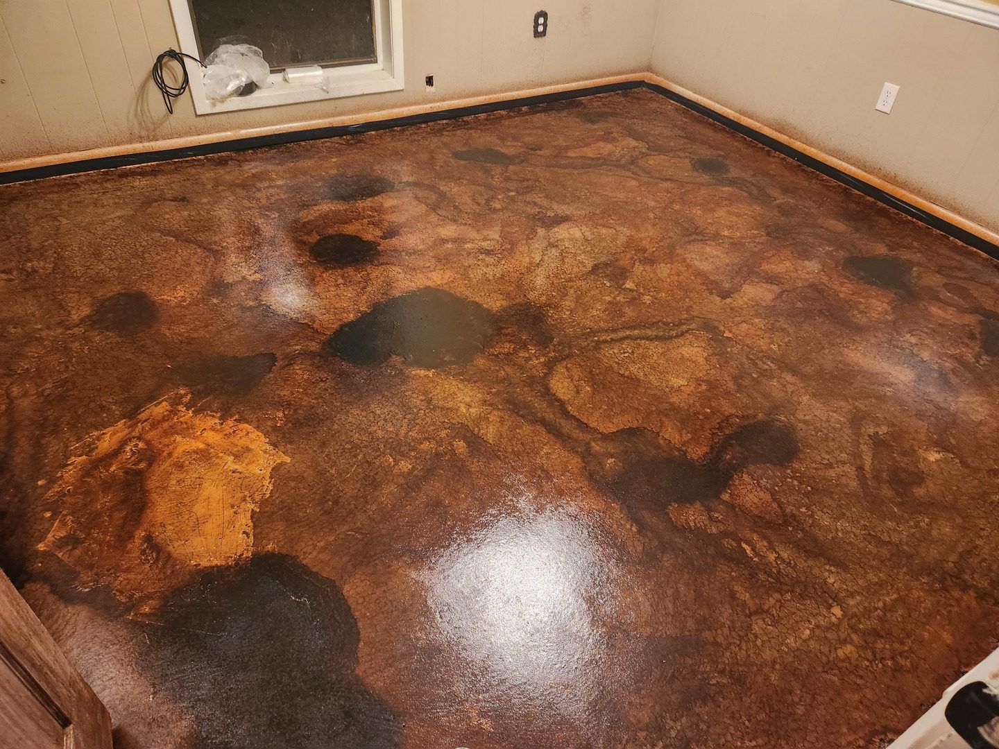 A smooth indoor concrete floor stained with ColorWave Mahogany and Molasses, showcasing rich brown tones and a glossy, polished surface