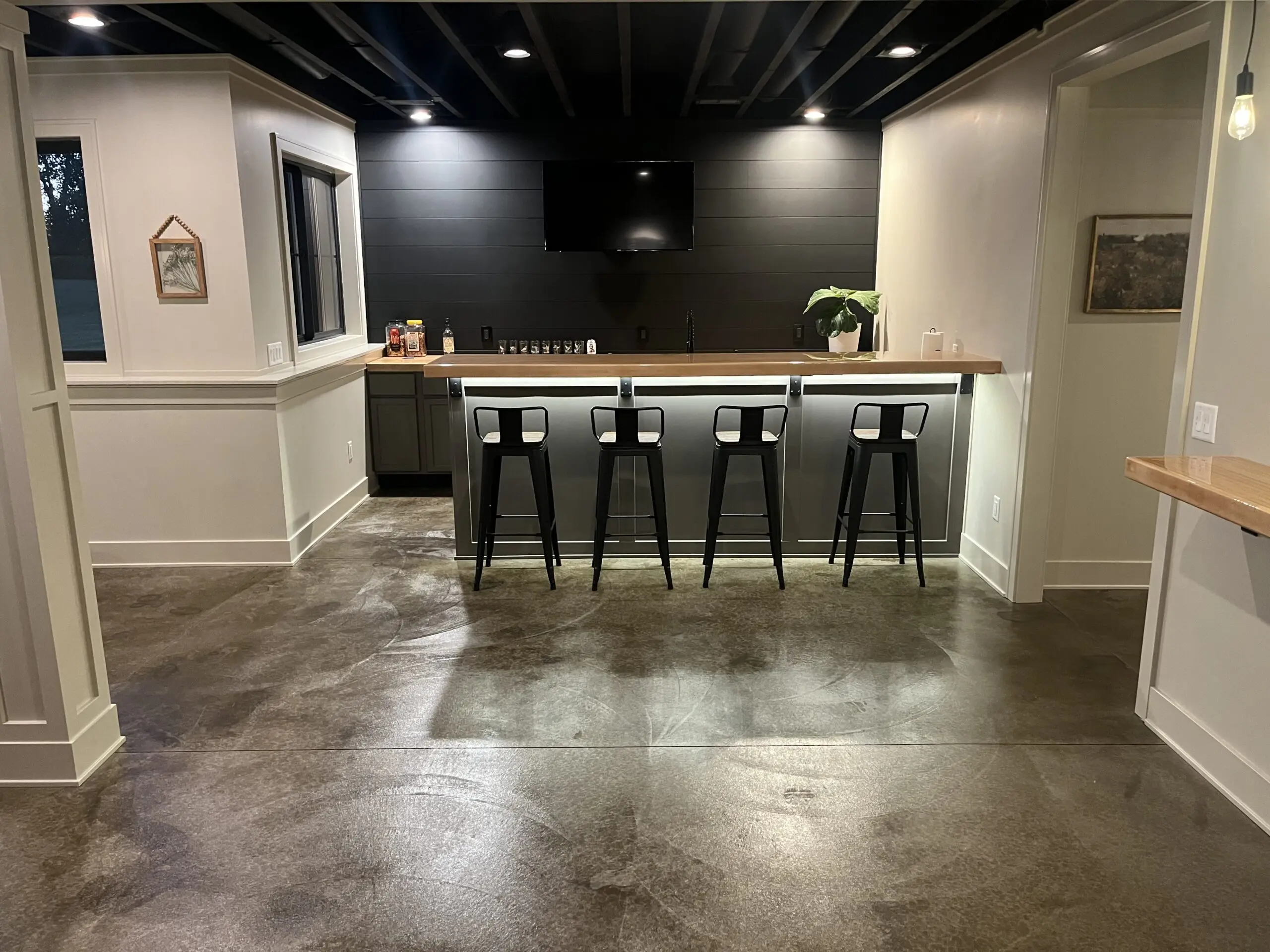 Bar area in a basement with a dark brown, polished concrete floor stained in Molasses ColorWave.