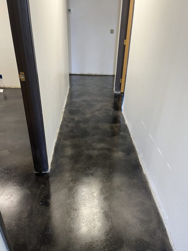 A smooth, polished concrete hallway floor stained in ColorWave Black and Steel Gray, reflecting a sleek and modern look.