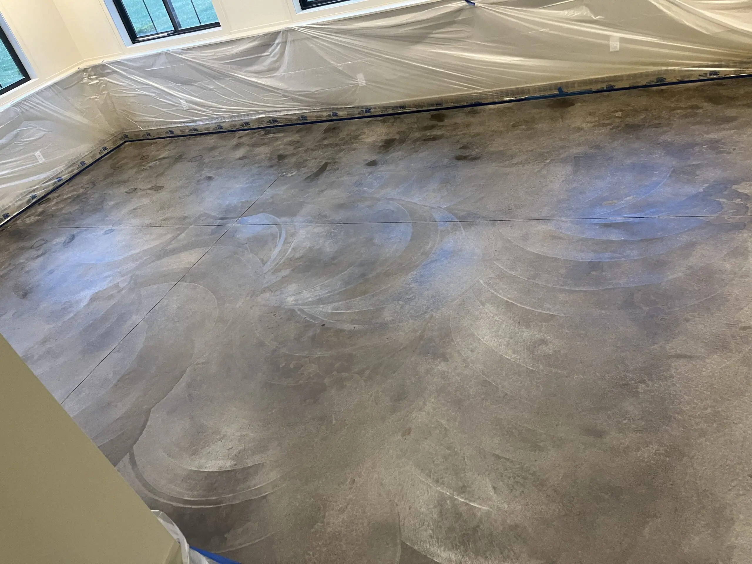 Concrete floor with Molasses stain applied, showing swirls and variations.