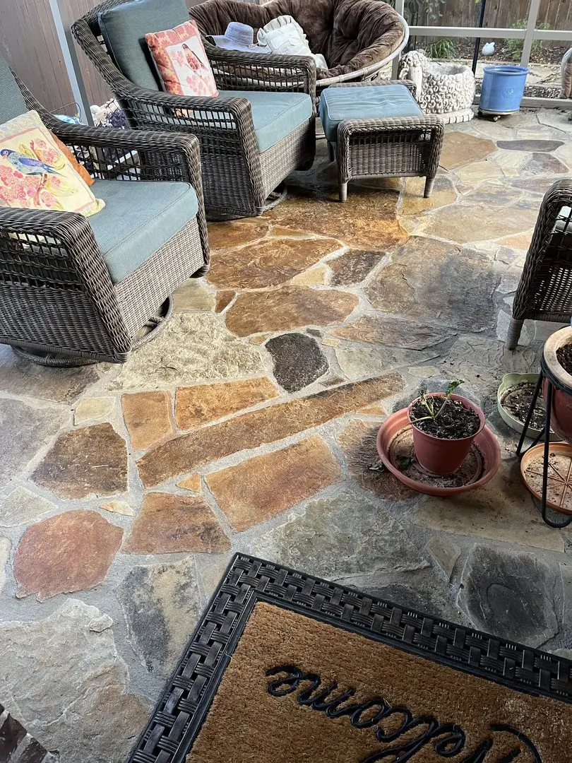 A flagstone patio featuring ColorWave stains in Rust, Amber, and Tangerine, with wicker furniture and potted plants enhancing the cozy outdoor space.