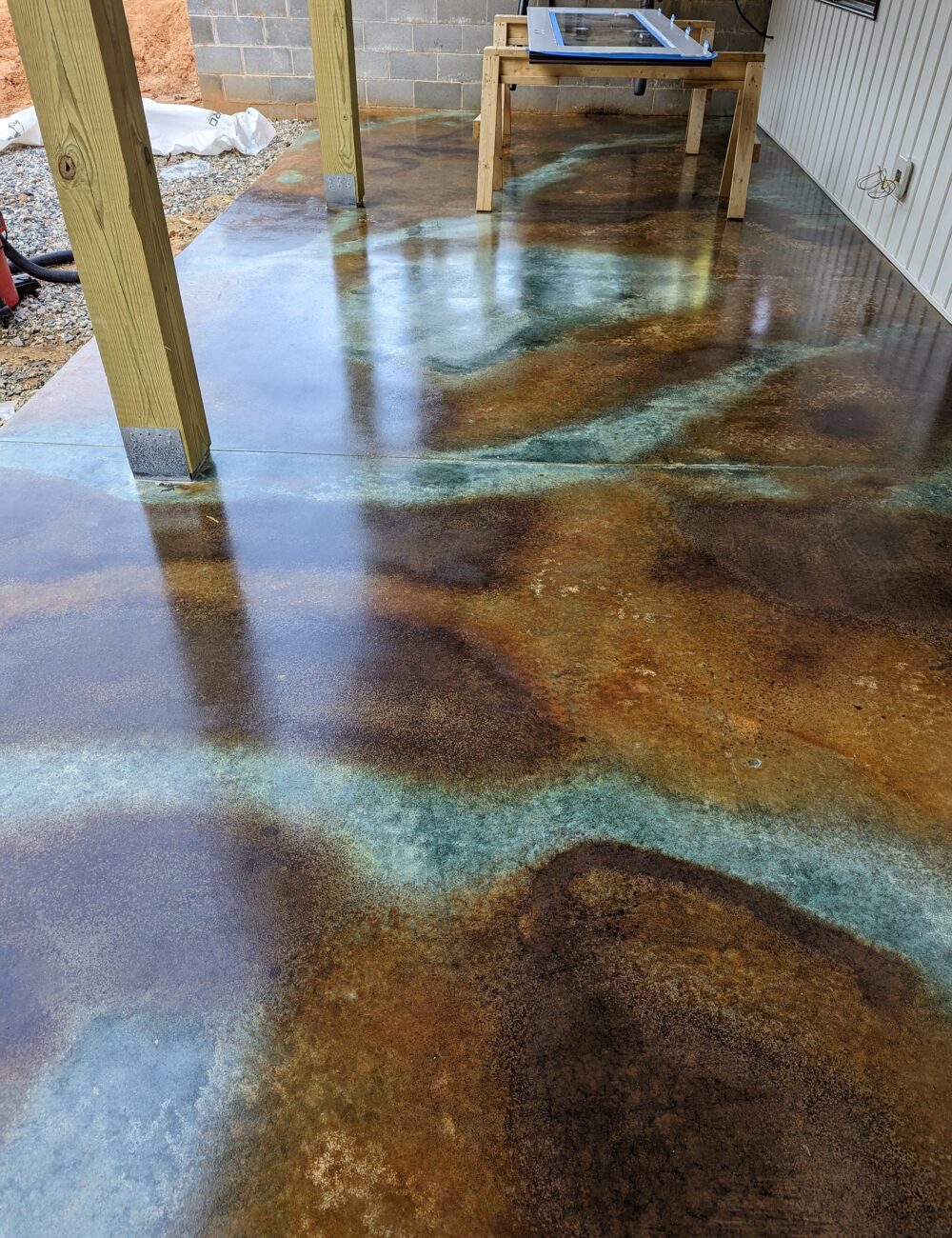 Concrete floor featuring a marbled design with freehand vein patterns using EverStain Coffee, Malayan Buff, and Seagrass acid stains, sealed with a glossy finish.