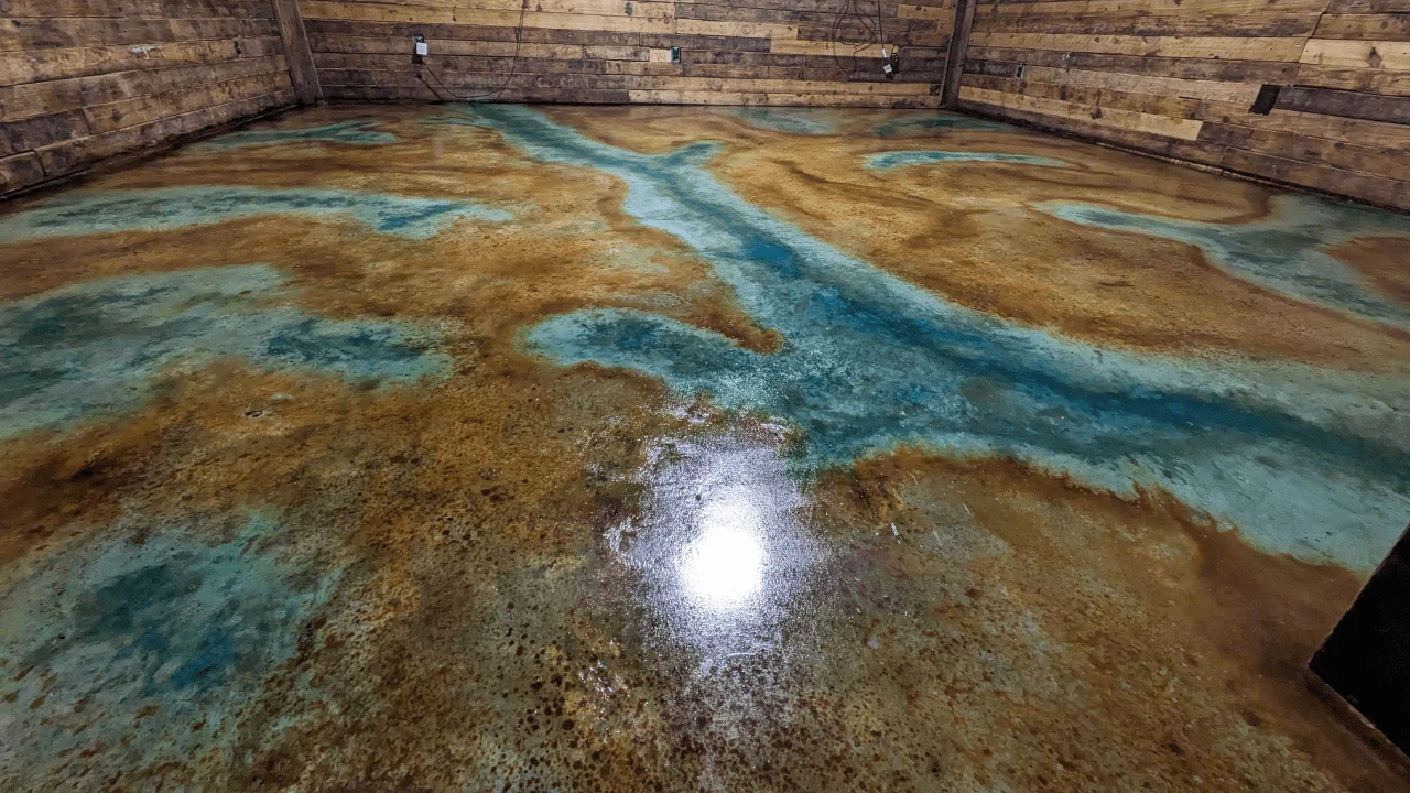 Farmhouse concrete floor with swirling patterns of EverStain Malayan Buff, Coffee Brown highlights, and seagrass acid stain enhanced with Miracle Gro granules.