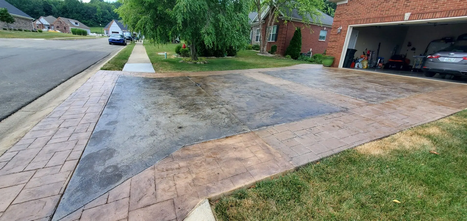 A stamped concrete driveway with contrasting sections stained in Molasses and Steel Gray, highlighting the textured surface with rich, complementary tones.