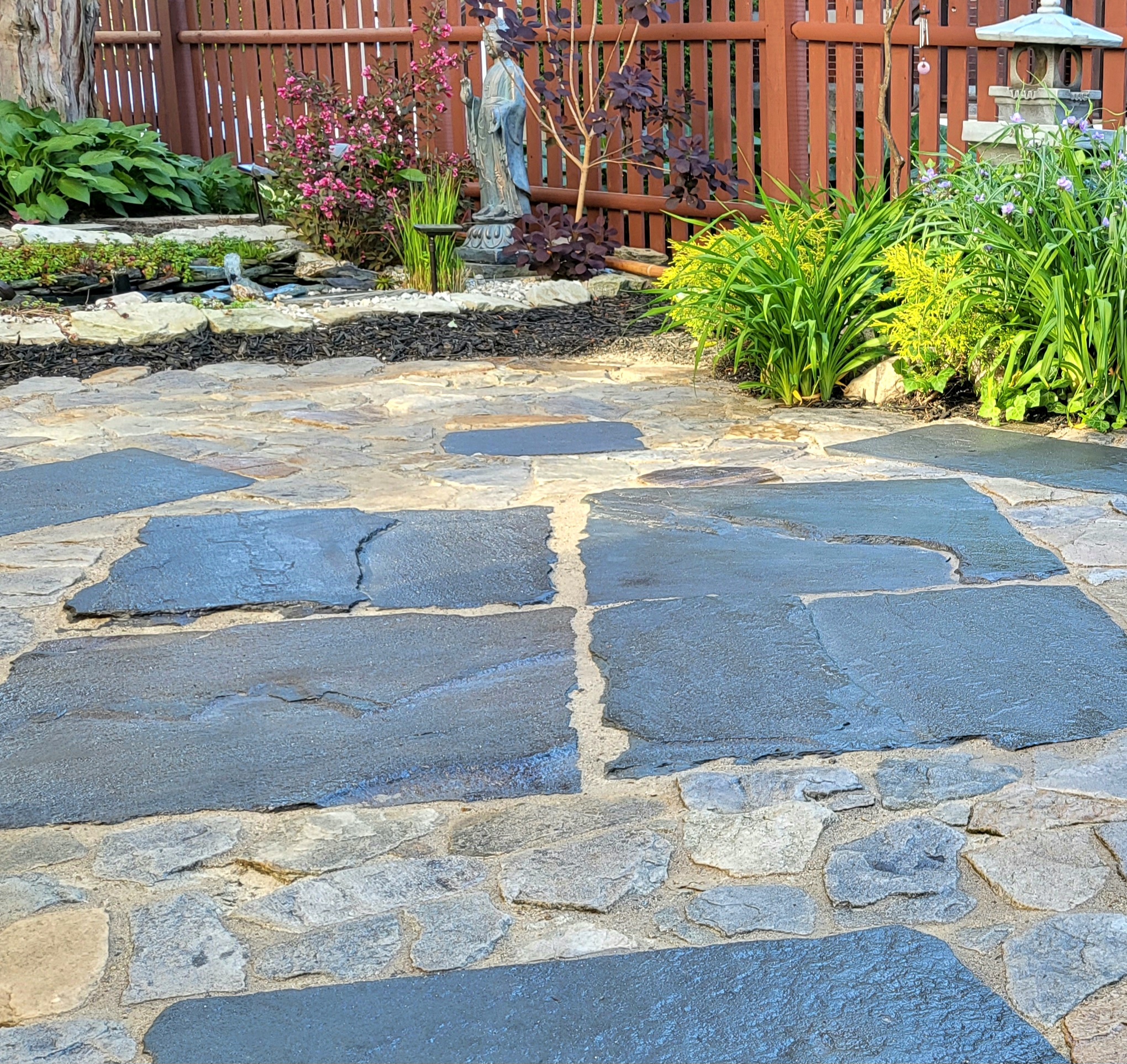 A DIY patio design featuring multicolored, slate-like stained stones, creating a serene and Zen-inspired backyard ambiance.