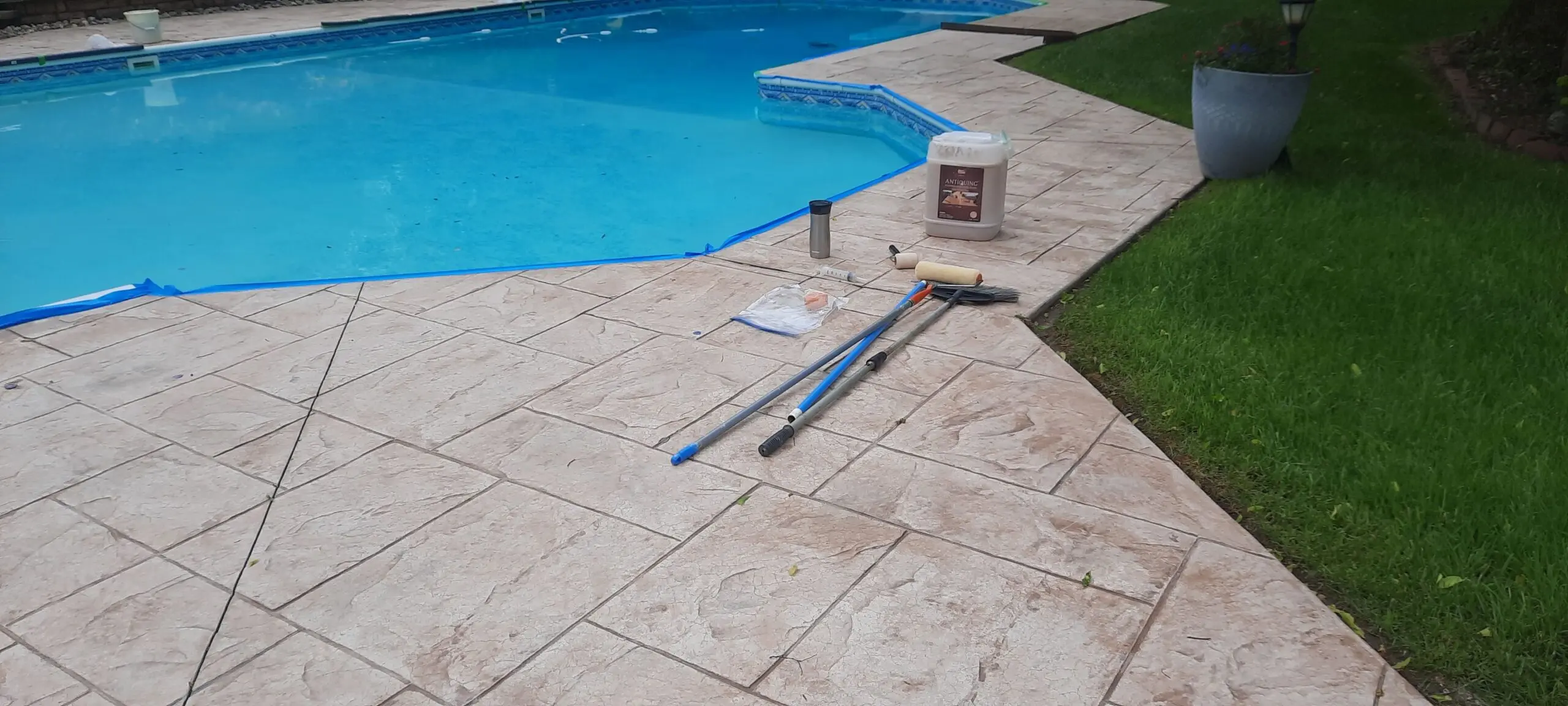 A faded stamped concrete pool deck before being restored with Tan Antiquing stain