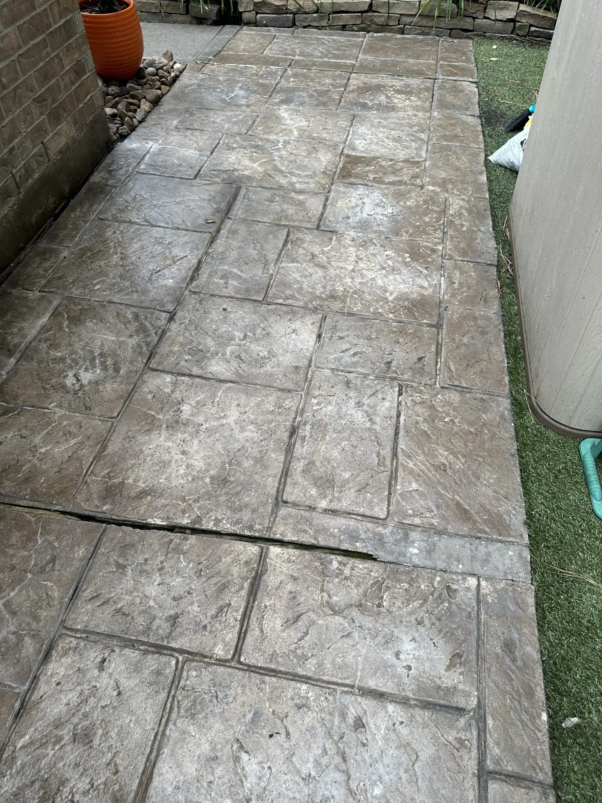 Discolored and faded stamped concrete, showing signs of wear and age.
