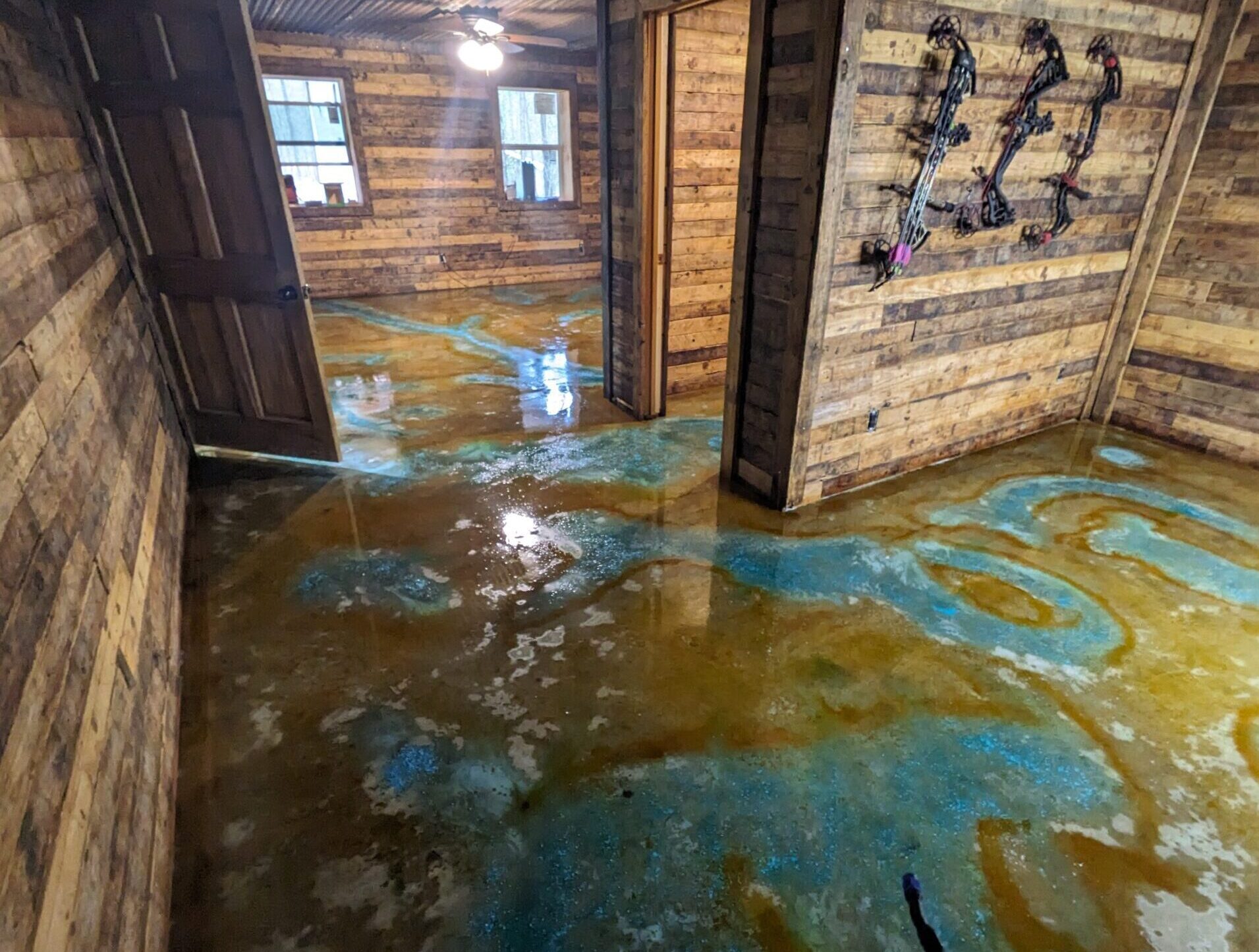 Acid stain applied with vibrant blue and amber tones on the shop floor, showing the wet application stage.