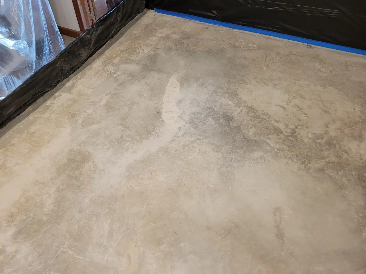 A freshly sanded and cleaned bare concrete basement floor, preparing for staining.