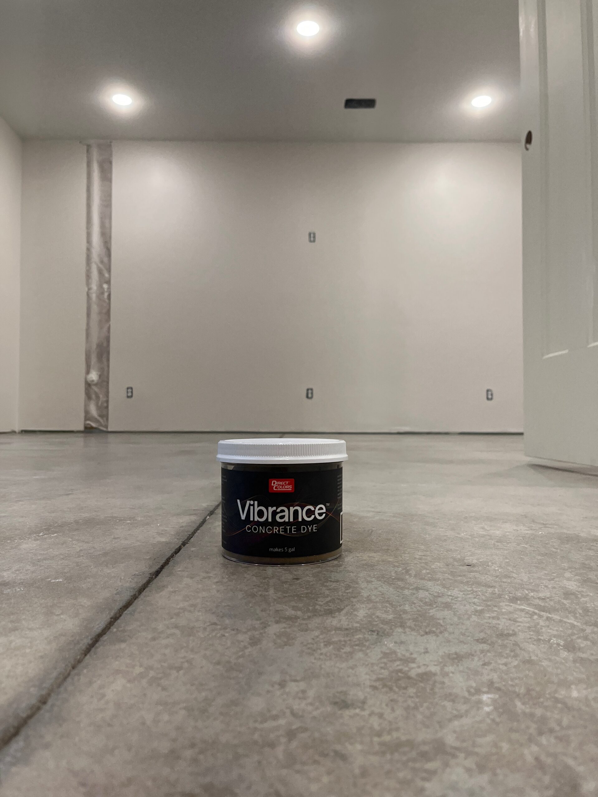 Before shot of the concrete basement floor with a container of Vibrance Dye Tweed on top