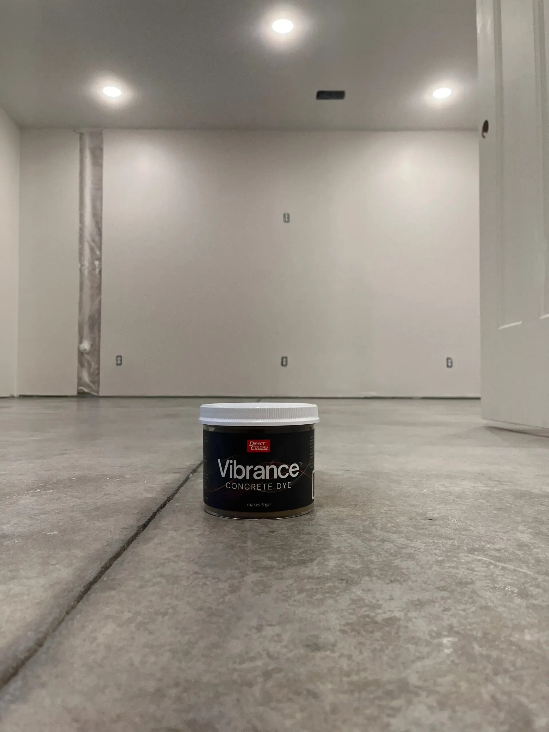 Before shot of the concrete basement floor with a container of Vibrance Dye Tweed on top