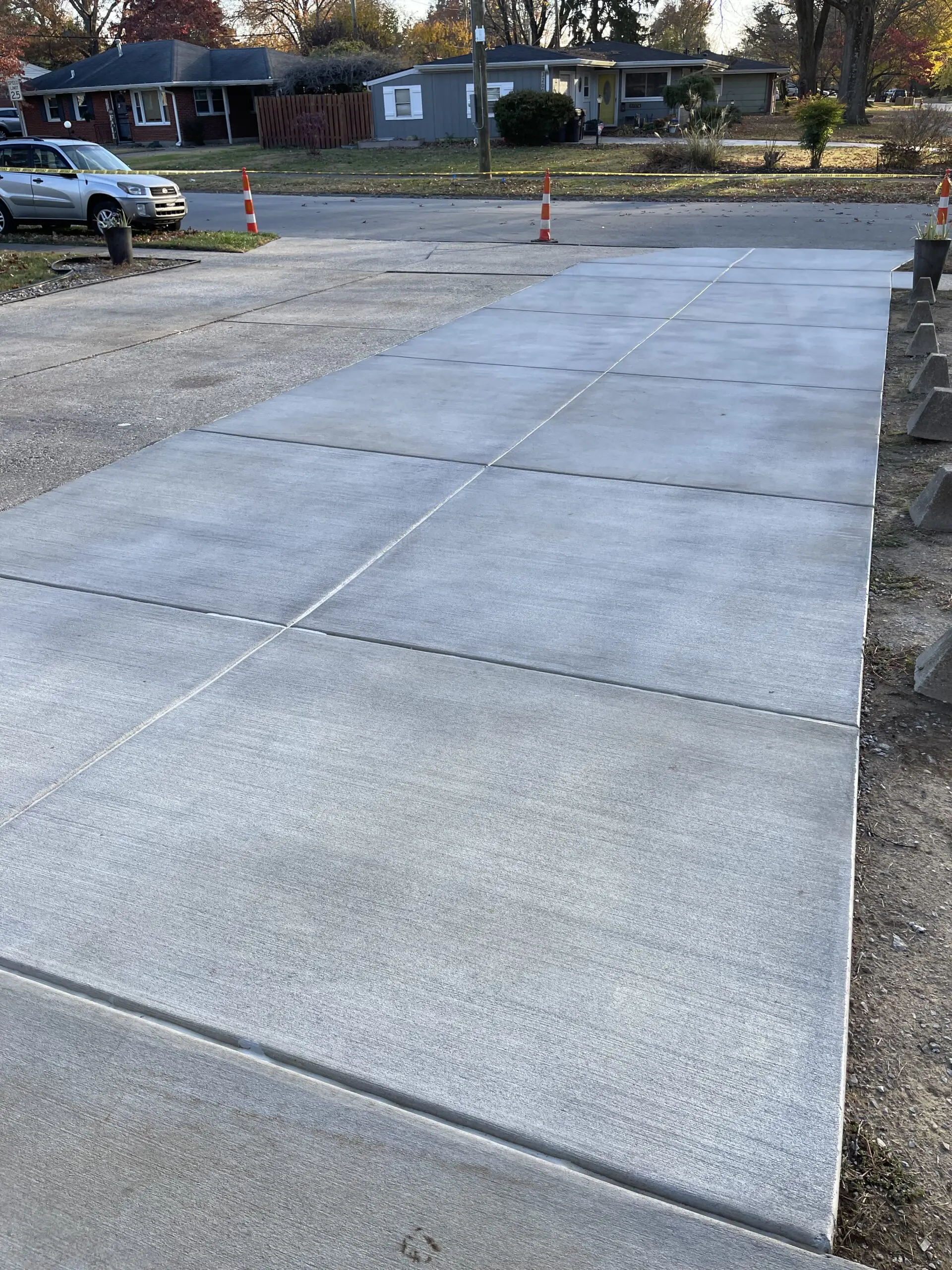 Unstained broomed concrete driveway in its original light grey color before the application of the stain.