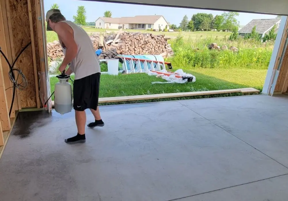DIYer using a pump sprayer to apply stain on the garage floor