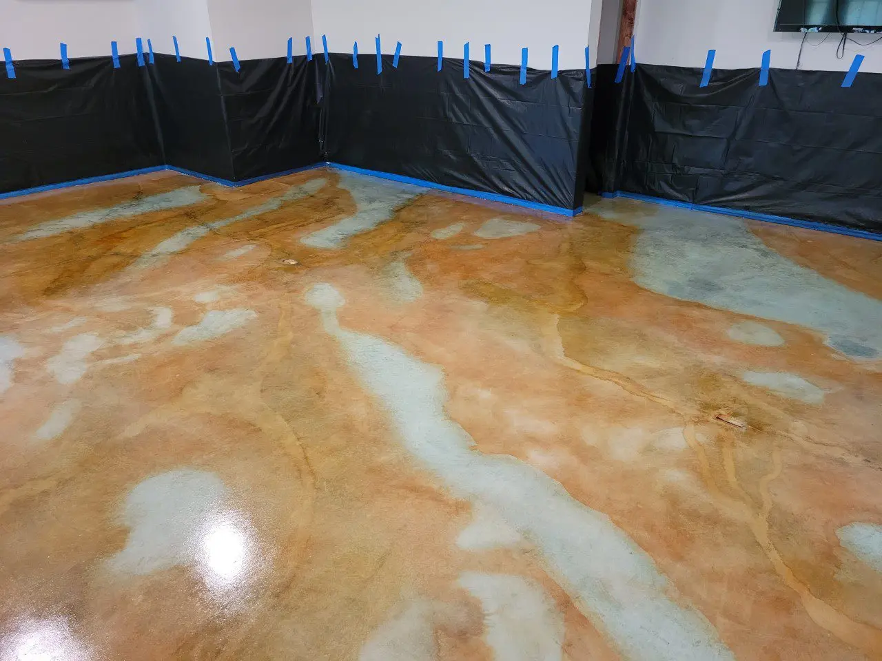 The stained concrete basement floor after application of a clear, glossy sealer enhancing the stain colors