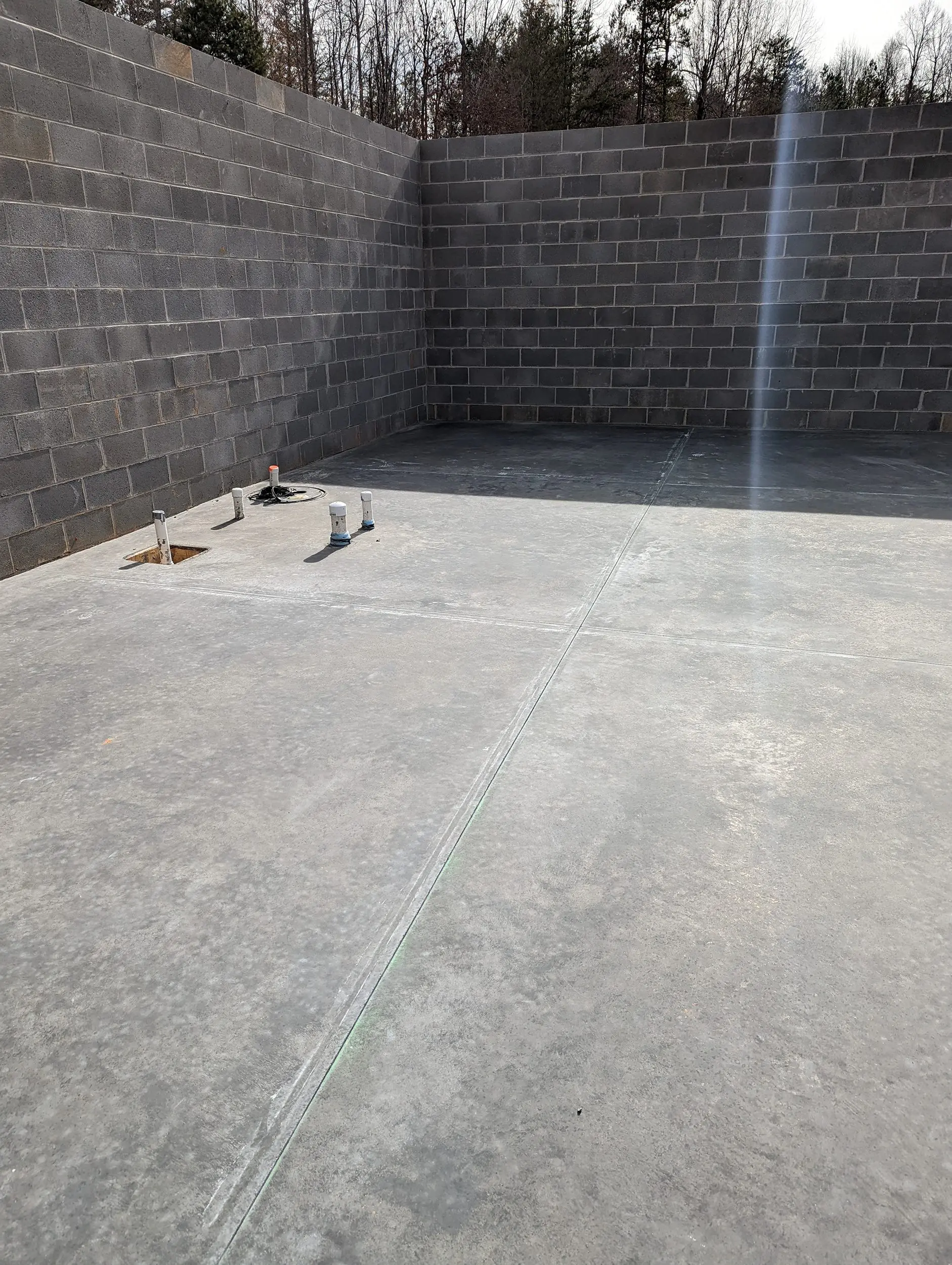 Newly constructed bare concrete floor in a basement awaiting staining