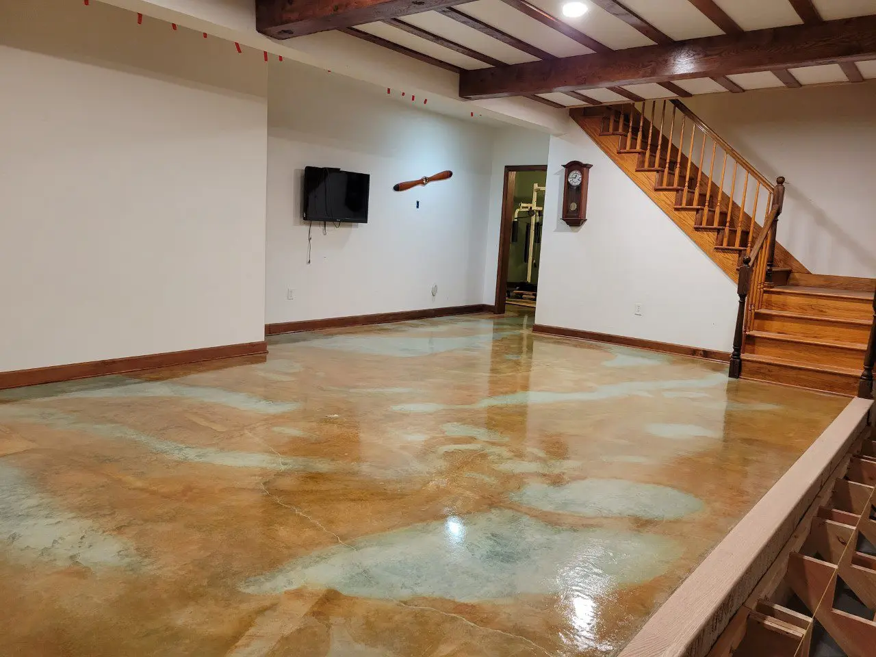 The completed stained, sealed, and waxed concrete basement floor, boasting richly pigmented colors and a beautiful, glossy finish