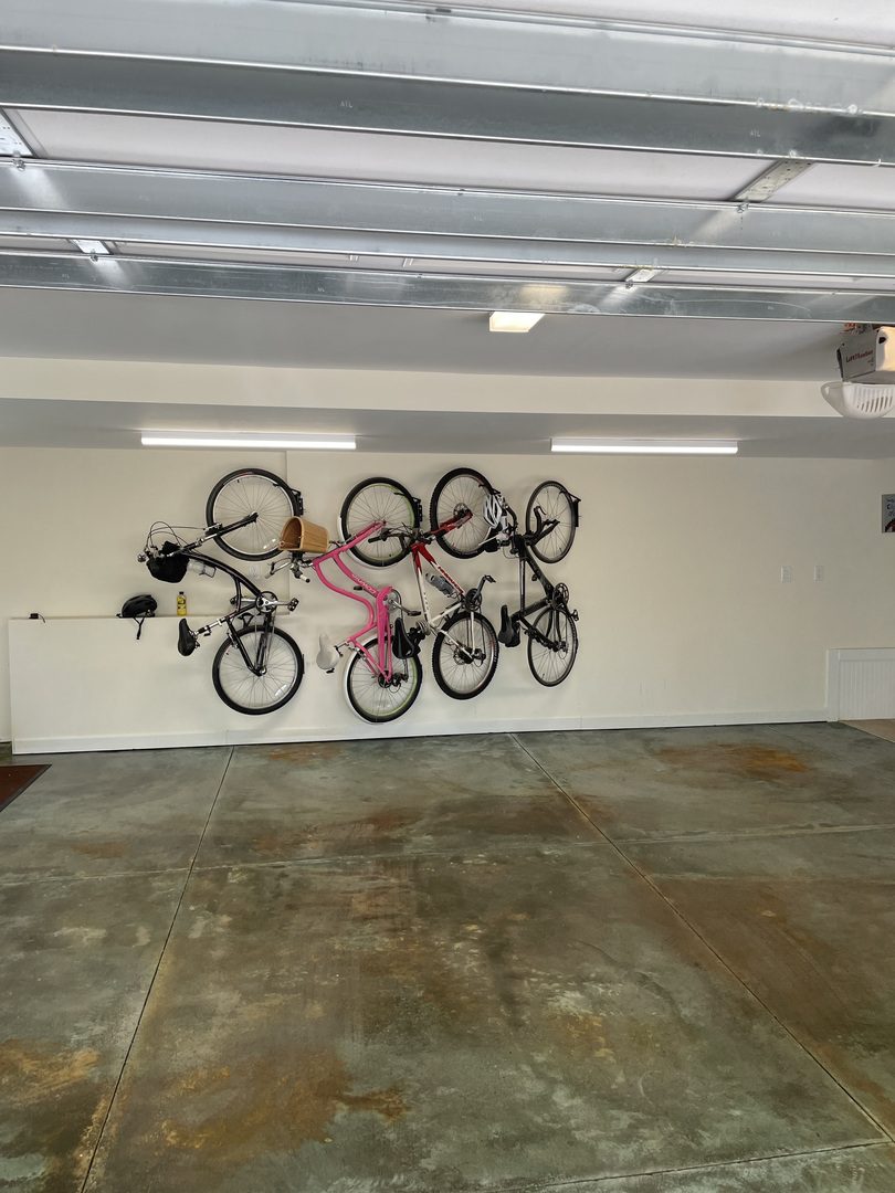 The serene green finished garage interior viewed from outside, showcasing a wall-mounted bike rack and bicycles hanging neatly