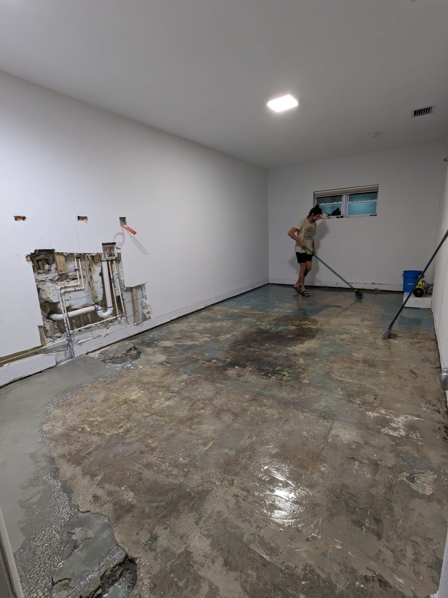 Prepping the space by grinding down the concrete floor and patching holes in the converted garage before applying the stain