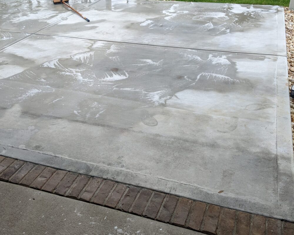 scrubbing the surface of an untreated concrete lanai floor before application