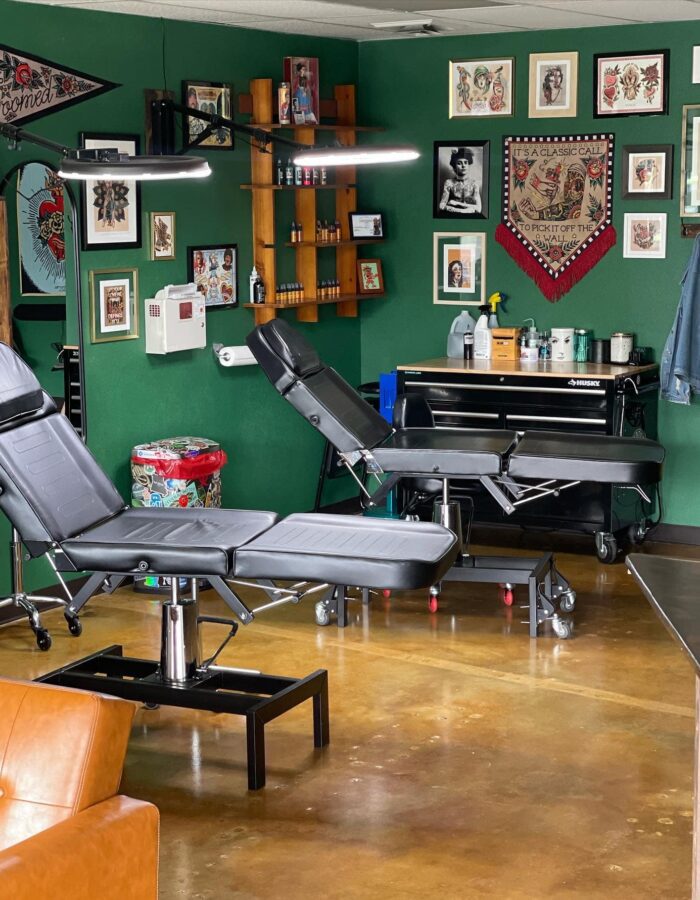A tattoo parlor with Malayan Buff and Shifting Sand acid-stained concrete floors, providing a glossy, mottled foundation that complements the vibrant green walls and eclectic decor