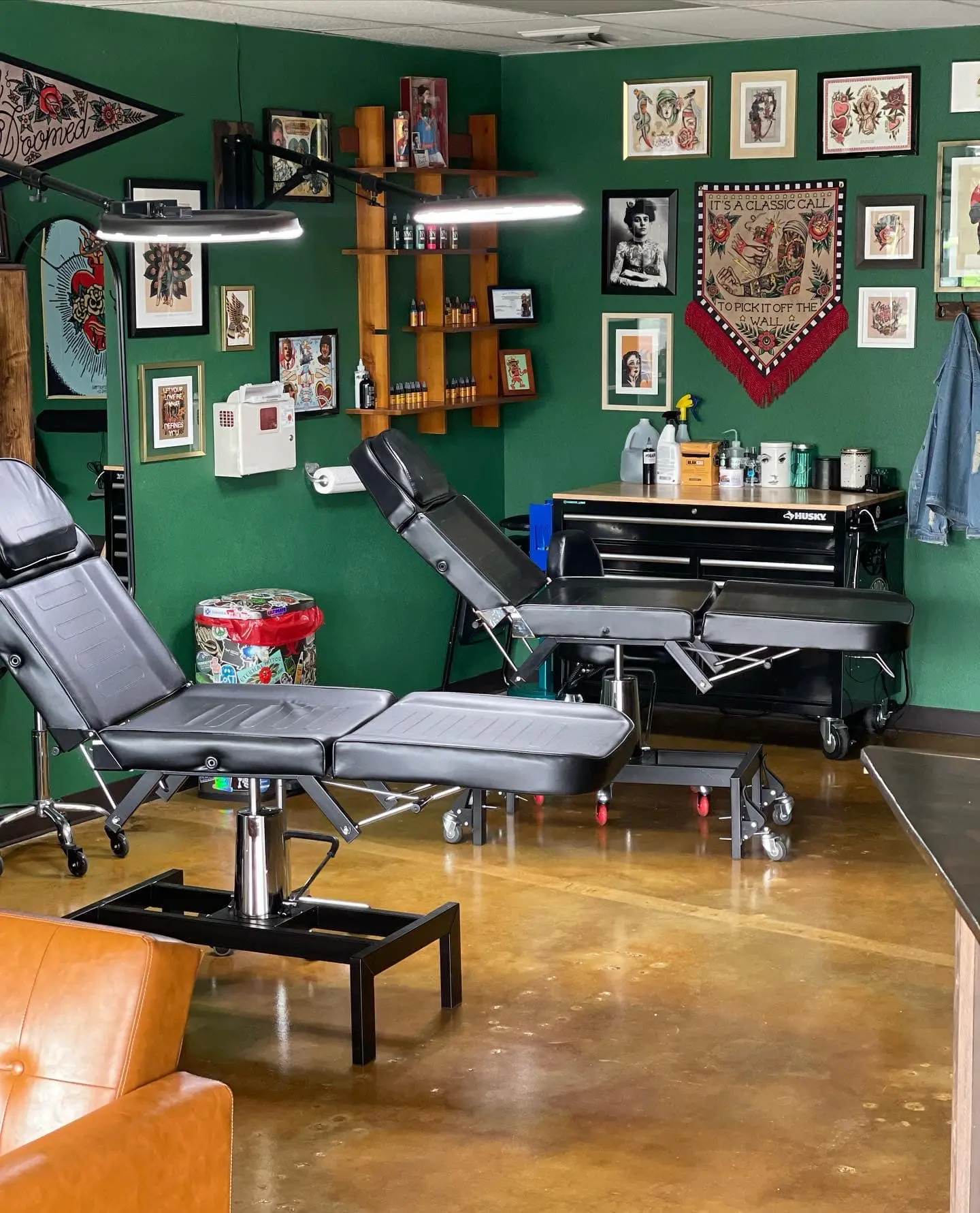 A tattoo parlor with Malayan Buff and Shifting Sand acid-stained concrete floors, providing a glossy, mottled foundation that complements the vibrant green walls and eclectic decor