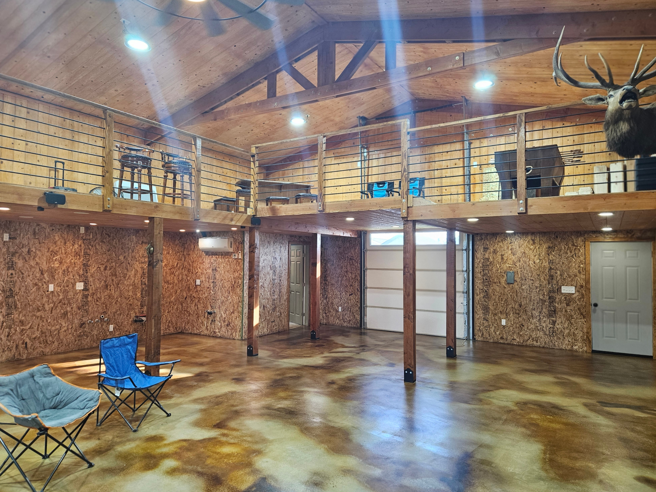A spacious interior with a high ceiling, showcasing a Coffee Brown, Cola, and Desert Amber acid-stained concrete floor, offering a rugged yet polished look