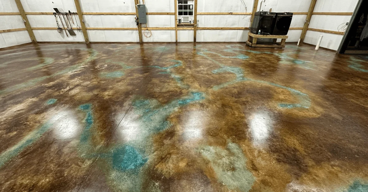 A spacious warehouse interior transformed into a polished floor with an intricate blend of azure blue, coffee brown, and English brown acid stains creating a rich, marbled effect.