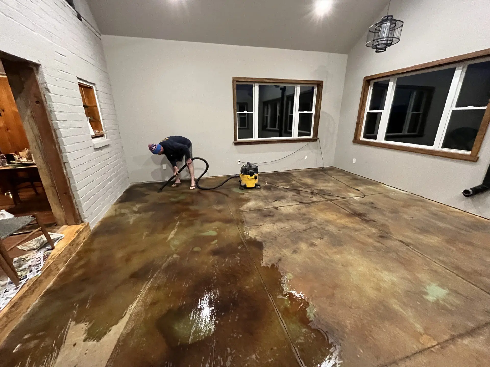 Worker applying acid stain on the concrete floor, creating an organic pattern.