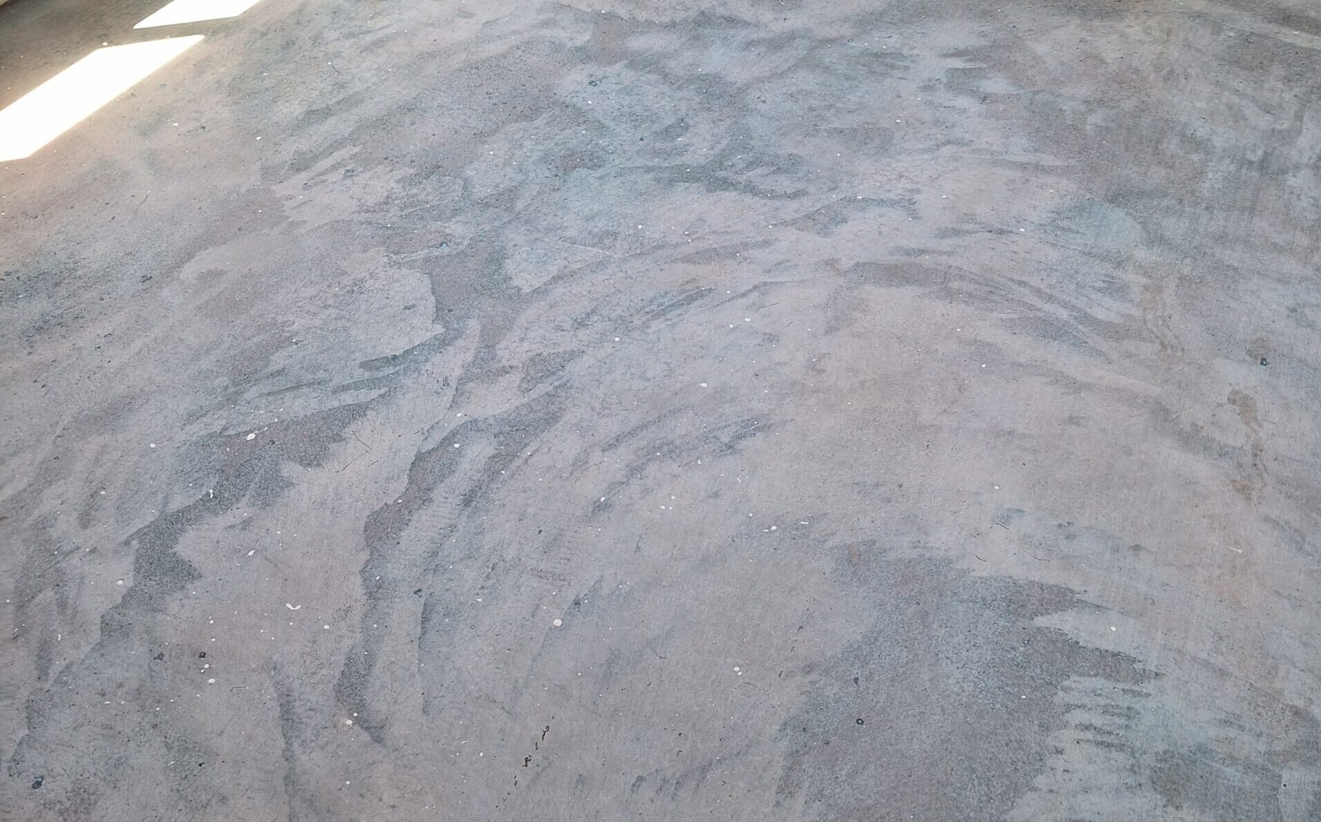 Concrete floor prepped for acid staining, showing a light texture and subtle variations before stain application.