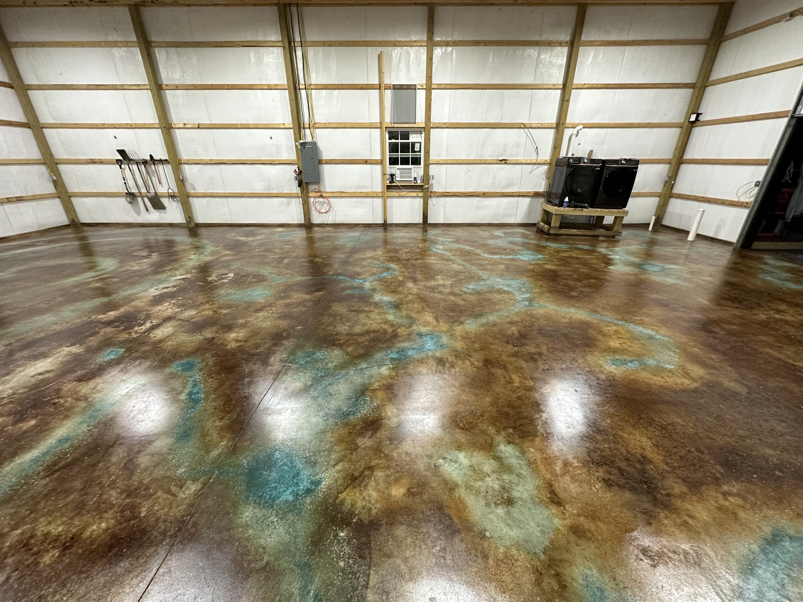 Finished concrete floor with a rich blend of Coffee Brown, English Red, and Azure Blue, featuring unique patterns created with Miracle Gro granules.