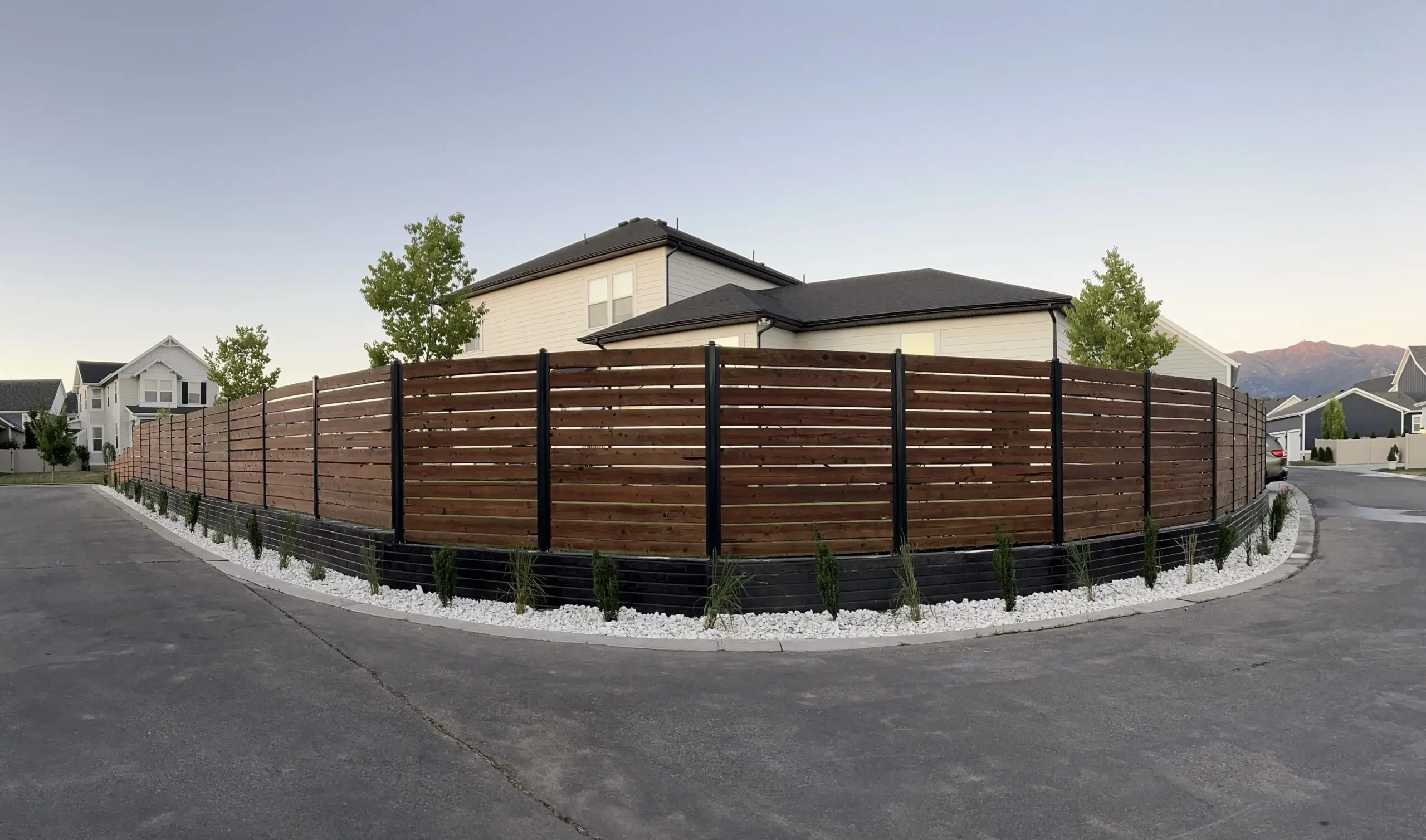 A backyard fence with a black concrete retaining wall and fresh landscaping