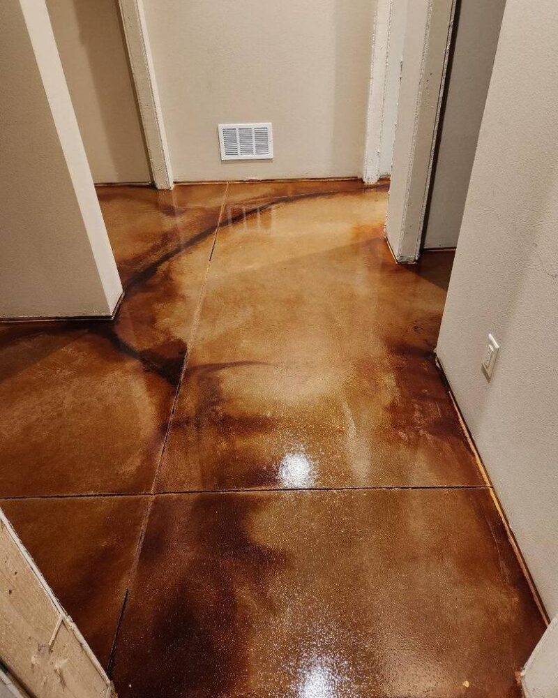 A hallway with a polished concrete floor featuring a blend of rich brown tones and dark veining created by acid staining.