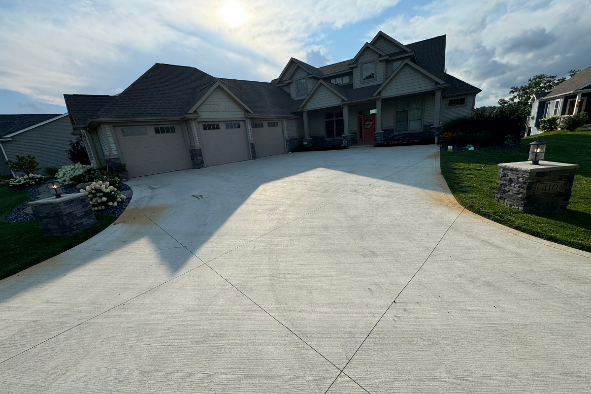Scored-broom-finished-driveway-before-buff-antiquing-stain Before photo of broom-finished concrete driveway showing weathering, staining, and fading prior to staining.