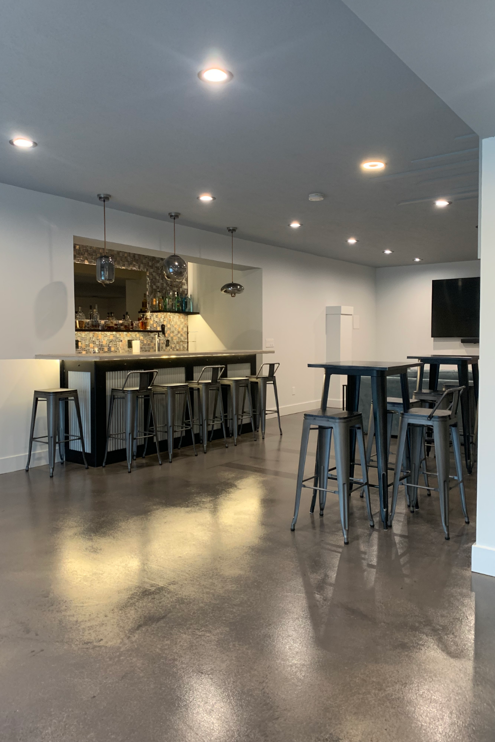 Sleek basement bar area with a stained concrete floor in black and gray AcquaTint