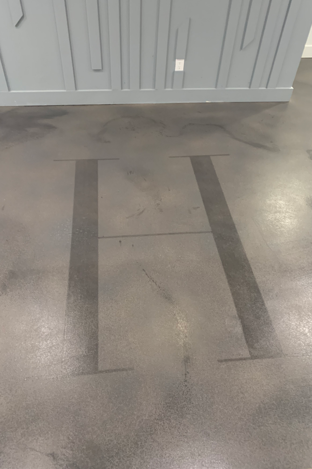 Stenciled letter "H" on a stained concrete basement floor