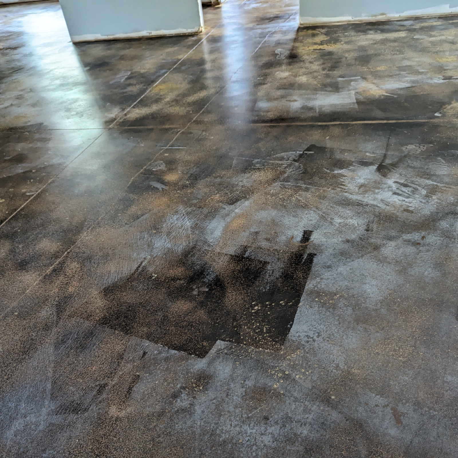 Checking the depth of color on a concrete floor by wetting the surface during the staining process.